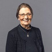 Woman with glasses wearing black clothes and smiling at the camera