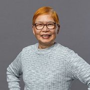 Asian woman with dark orange dyed hair and glasses smiling at camera